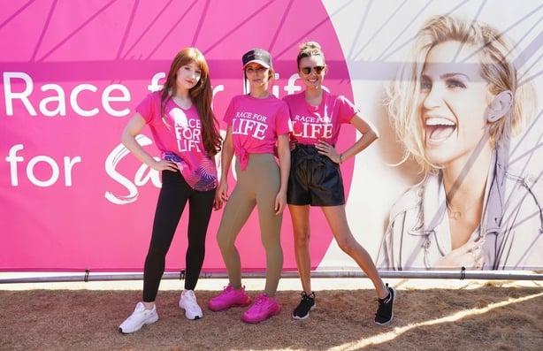 Three women wearing pink t-shirts in front of a banner that reads 'Race for Sarah'