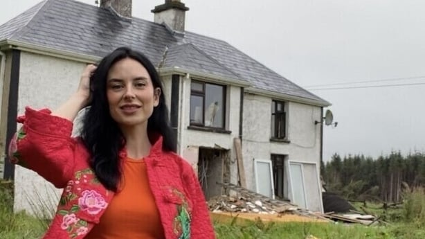 A woman standing outside a 100-year-old farmhouse