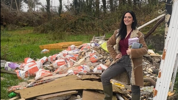 A woman standing outside beside a pile of wood