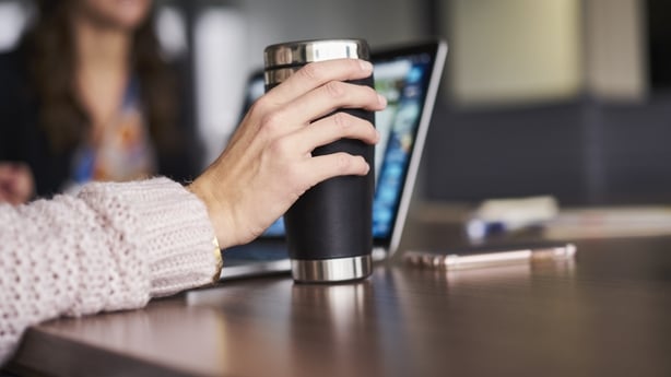 Reusable steel cup on a desk in front of a laptop and mobile phone during a meeting