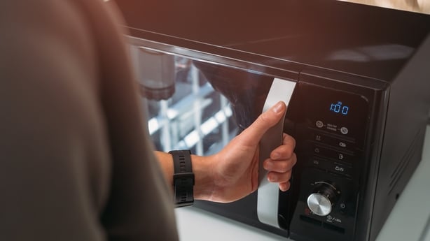 Close up of man using microwave in kitchen