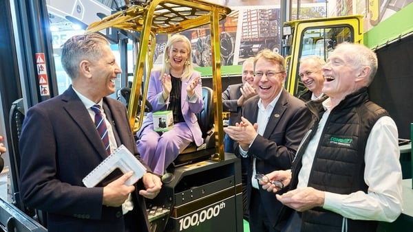 Picture of a group of happy people around a yellow forklift truck