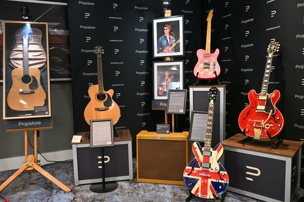 A collection of guitars used by Noel Gallagher of Oasis including (L-R) Noel Gallagher's Takamine FP460SC Acoustic Guitar, his autographed Pink Paisley Fender Telecaster Guitar, his autographed Limited Edition Epiphone Union Jack Sheraton Guitar, and his 1960 Cherry Red Gibson ES-355 guitar, famousl