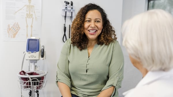 An unrecognizable senior adult female doctor listens attentively to the mid adult woman.