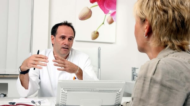 A male doctor speaking to a female patient in an office