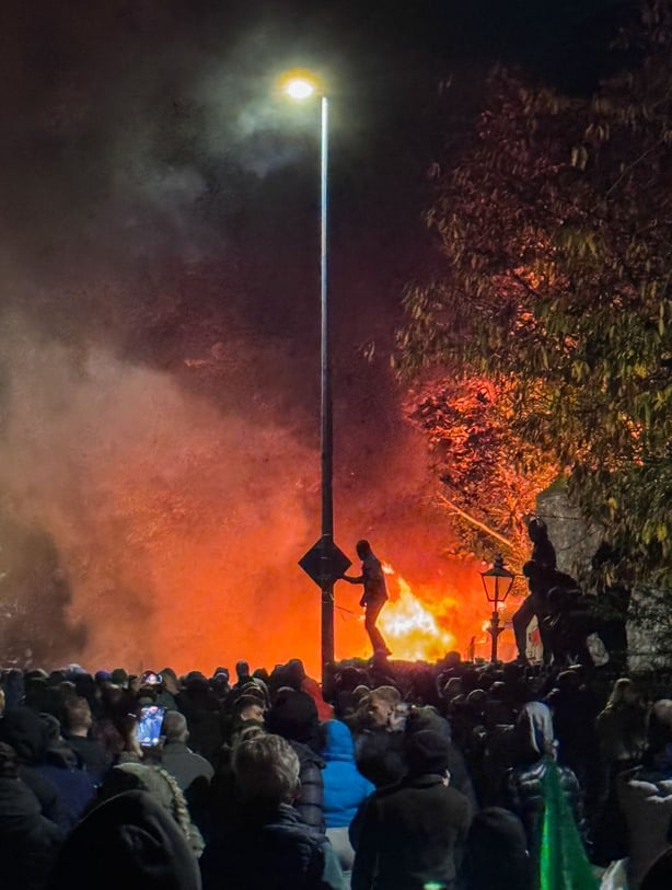 Demonstrators near a burning garda van
