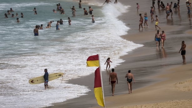 People swim and walk along Bondi Beach on a hot and windy spring day in Sydney