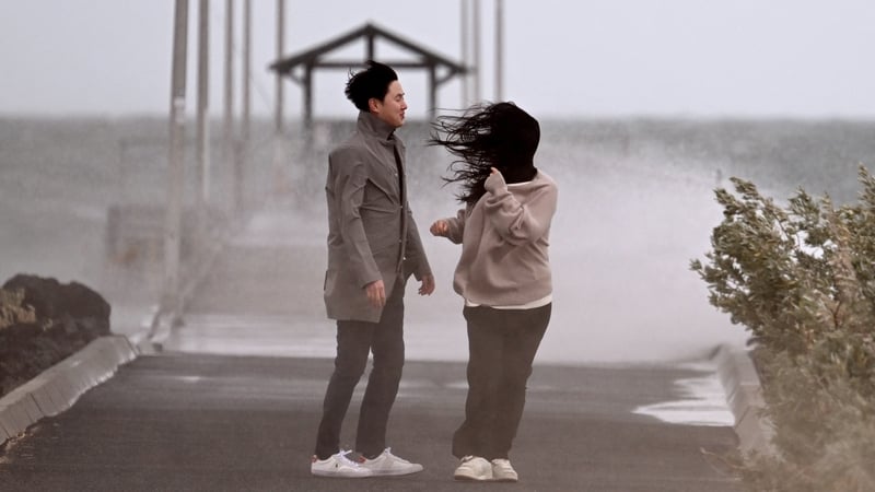 People stand near a jetty in stormy weather in Melbourne