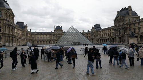 Visitors mill around the pyramid entrance to the museum in Paris