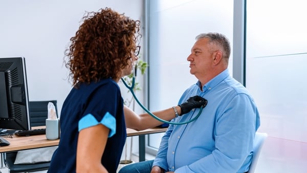 A female doctor using a stethoscope on a patient's chest at a medical