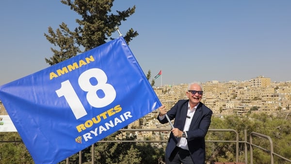 Picture of a man in a suit and sunglasses waving a big blue flag with Ryanair routes on it
