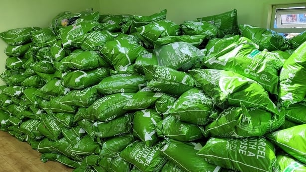 Image of piles of green 'Postback' donation bags ready to be sorted