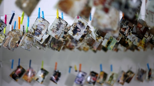 Dozens of colourful pegs are pinning damaged photographs to a line of string