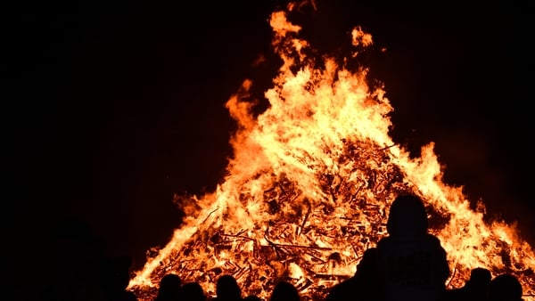A raging bonfire glowing brightly in the dark night sky, colours of oranges, yellows and red
