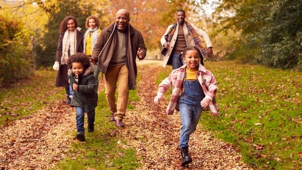 Smiling Multi-Generation Family Having Fun With Children Walking Through Autumn Countryside Together
