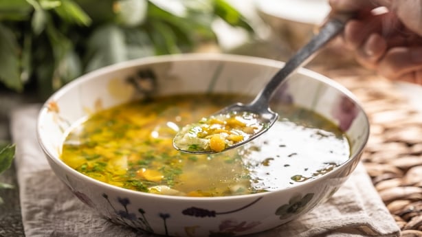 Healthy vegetable soup from fresh spring vegetables. A close-up view of a spoon full of hot soup. Healthy spring vegetable soup, cooked from carrots, parsley, kohlrabi and spring onion, added chopped parsley.