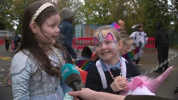 Two girls in fancy dress are interviewed on TV.