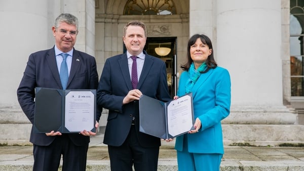 Picture of two men and a woman holding up copies of a new bank loan agreement
