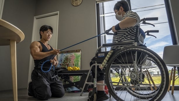 Hokuto Tatsumi helps a woman train at a care home for people with disabilities