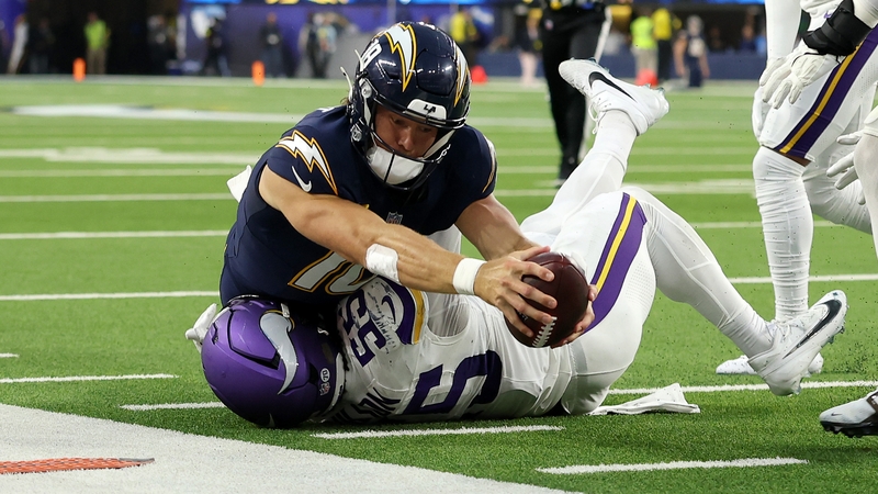 The Los Angeles Chargers' Justin Herbert (top) reaches for a first down against Eric Wilson of the Minnesota Vikings