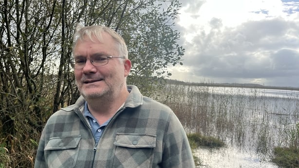 A photo of John Horan with a lake in the background