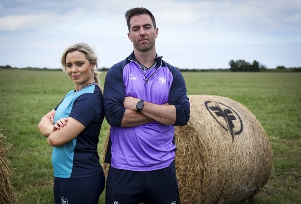 Anna Geary and Michael Darragh MacAuley posing beside a hay bale