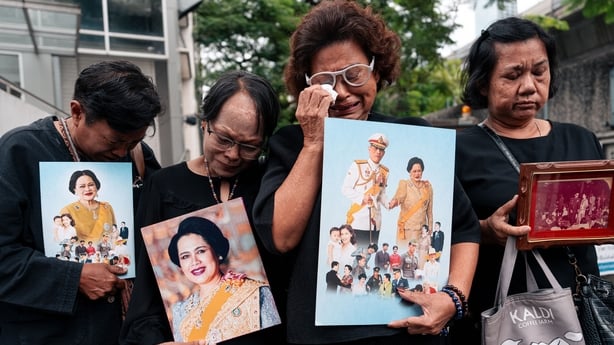 BANGKOK, THAILAND - 2025/10/25: Mourners, dressed in black and holding the royal portrait of Her Majesty The Queen Mother, gathered in front of Chulalongkorn Hospital to pay their respects. The Royal Household Bureau announced the passing of Her Majesty Queen Sirikit The Queen Mother peacefully at K