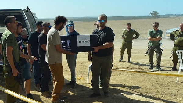 Former hostage Yossi Sharabi's coffin is carried from a van to his funeral as IDF soldiers look on