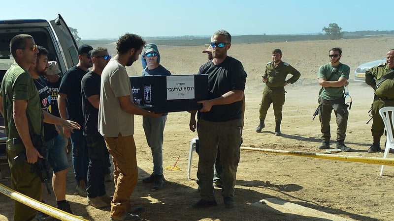 In an earlier handover, the remains of former hostage Yossi Sharabi are carried from a van as IDF soldiers look on