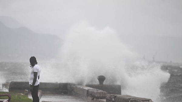 A man watches the waves crash into the walls at the Kingston Waterfront