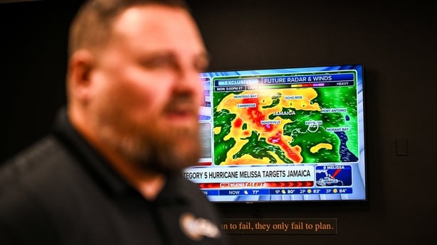A weather news channel displays Hurricane Melissa updates