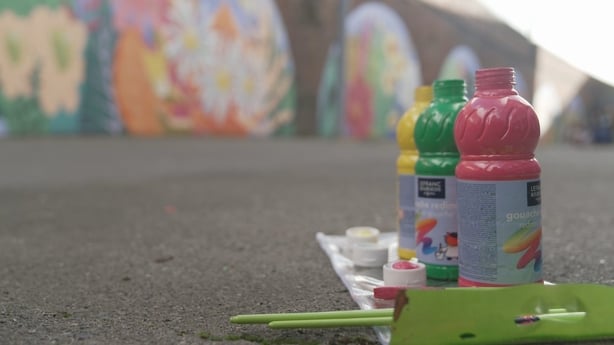 Bottles of poster paint in the foreground with murals in the background