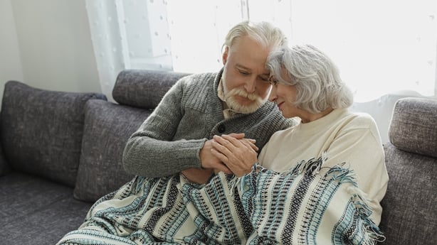 Senior couple cuddling on the couch under a blanket