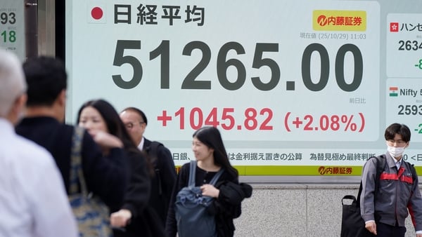 Pedestrians walk past an electronic quotation board displaying numbers of the Nikkei index in Japan