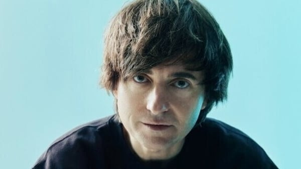 Danny Robins close-up looking directly into camera with a light blue background