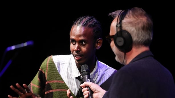 writer Sage Omar discussing his 2025 RTÉ Short Story Competition shortlisted story with Arena presenter Rick O'Shea, on stage at awards night, Oct 2025