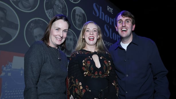 smiling three winning writers of the 2025 RTÉ Short Story Competition (l to r: Angela Fin, Lynda McCarthy and Ian Feighery), on stage at awards night in Pavilion Theatre Dun Laoghaire