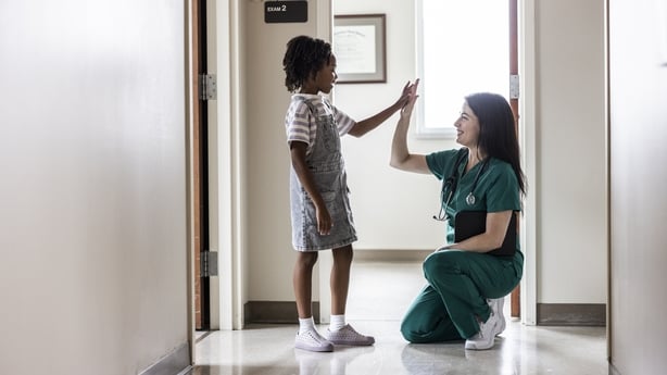 Female doctor hi-fiving young girl in hallway