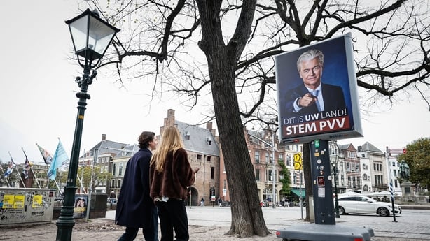 Pedestrians walk past a campaign poster of the president of the far-right Party for Freedom (PVV), Geert Wilders