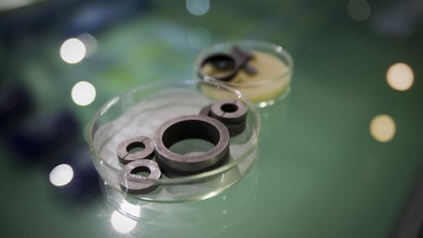 Four circular shaped magnets sit in a clear plastic dish on a green table.