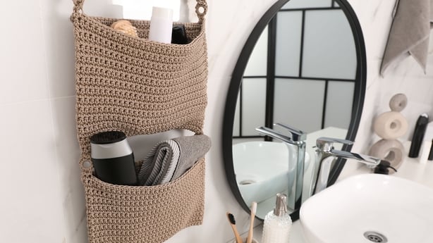 Knitted organizer hanging on wall in bathroom