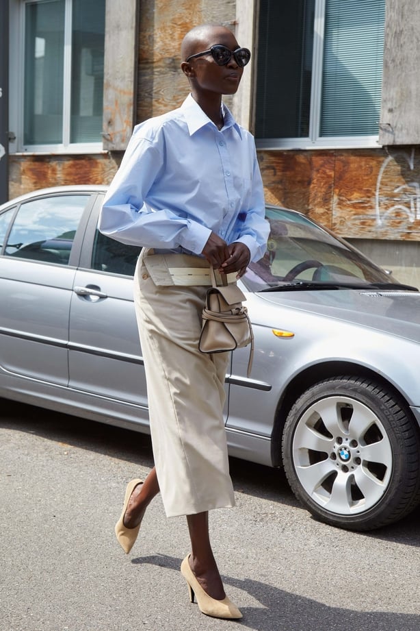 A woman wearing a blue shirt and a cream skirt