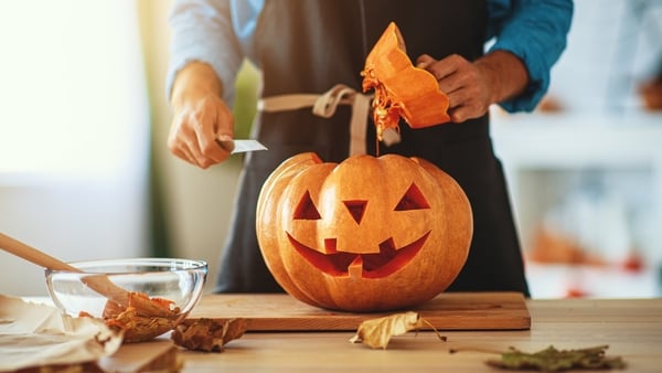 hands of man carving a pumpkin at halloween