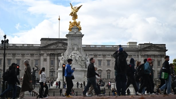 Pedestrians walk by the Queen Victoria Memorial outside Buckingham Palace in London