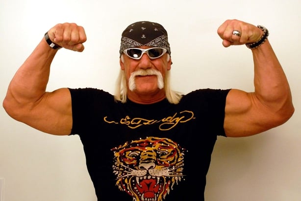 A photo of Hulk Hogan wearing an Ed Hardy top, bandana, sunglasses and flexing his muscles