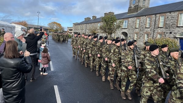 Members of the Defence Forces marching outside a barracks as members of the public watch on