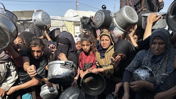 Palestinians hold out bowls as a charity distributes
