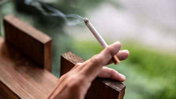 A person holds a lit cigarette in their hand