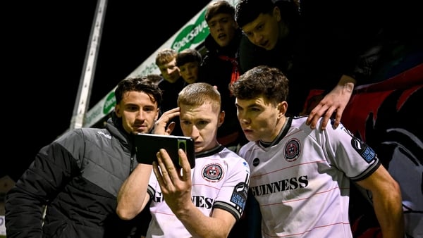 1 November 2025; Bohemians players, from left, Connor Parsons, Ross Tierney and James Clarke and Bohemians supporters view a smartphone for the closing minutes of the Shelbourne v St Patrick's Athletic match after the SSE Airtricity Men's Premier Division
