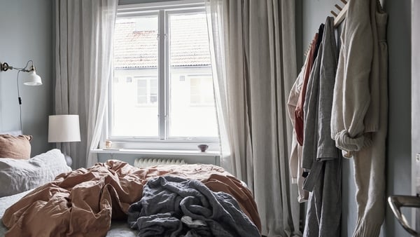 a bedroom with clothes on wall pegs